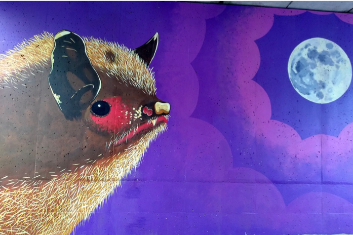 A mural depicting a bat with a purple sky and the moon in the background