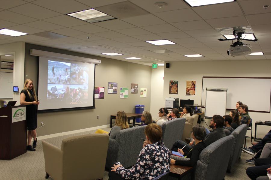 Stefani Crabtree giving a presentation to a group of people gathered at SESYNC