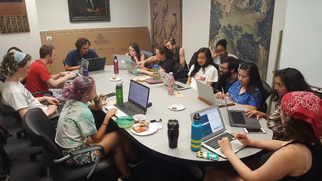 A group of people around a table with laptops working on data analysis