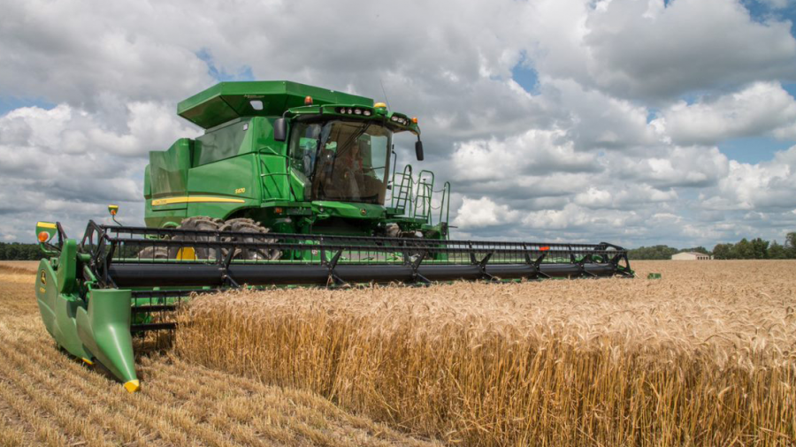 A piece of large farming equipment, a combine, cutting wheat from a field