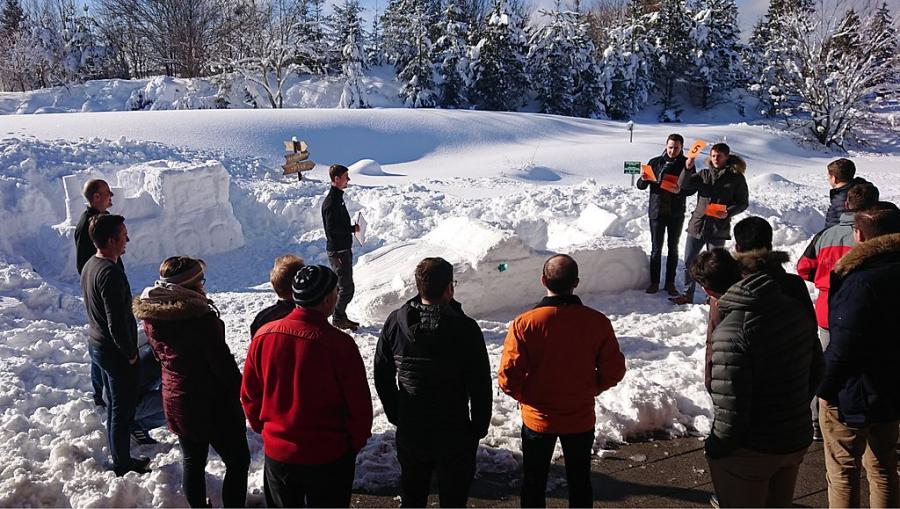 A photo of a group of people standing around some snow sculptures engaged in some sort of activity