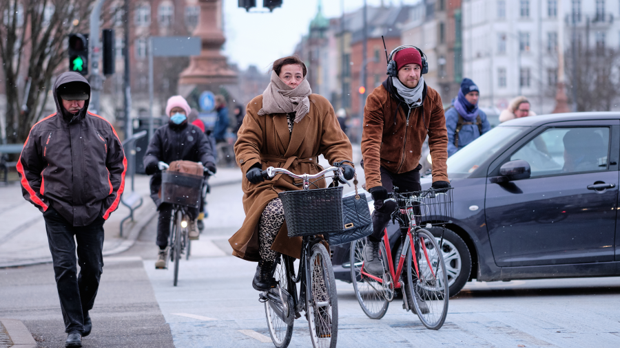 People commuting via bicycle on a roadway with a car in the background