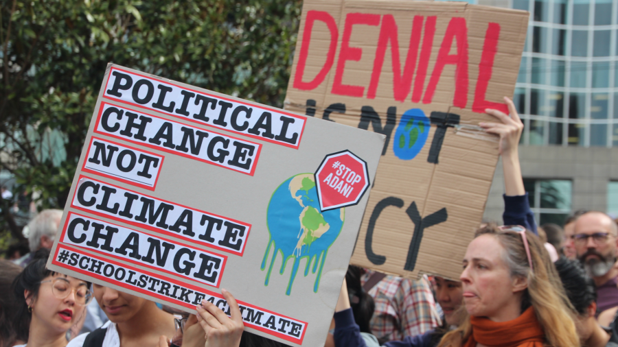 Protesters carrying signs at a demonstration—one of which says, "Political change not climate change"
