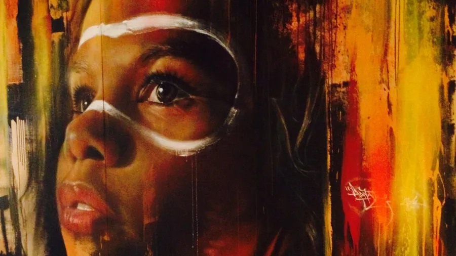 A painting of a closeup of an Aboriginal Australian’s child’s face with white face paint around the eyes.