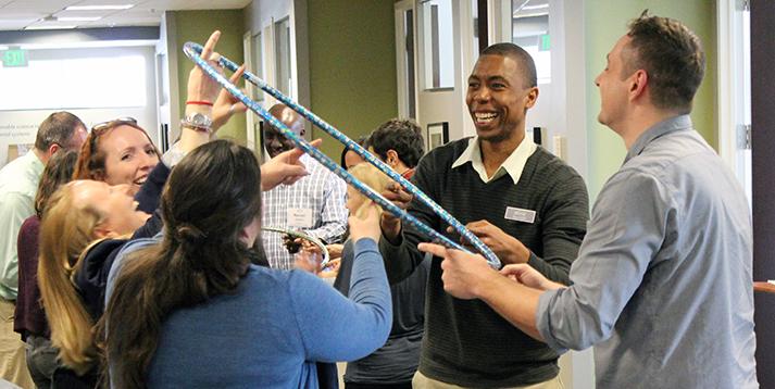 A group of people laughing while engaged in an activity involving a hula hoop