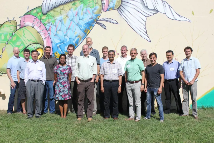 The Living with Resistance synthesis team stands in front of a wall outside painted with a mural of a fish