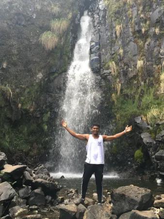 A picture of Damani Eubanks standing in front of a waterfall