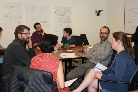 Several people seated around a table engaged in a discussion