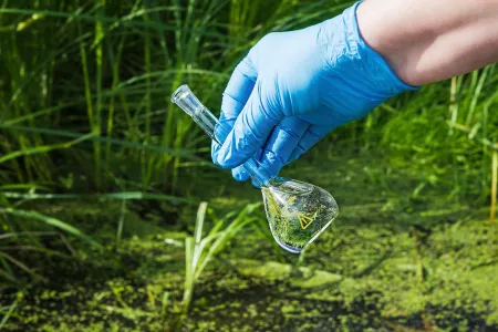 A gloved hand taking a water sample