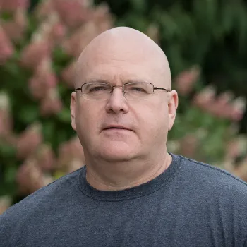 Dr. Beckage stands in front of flowers