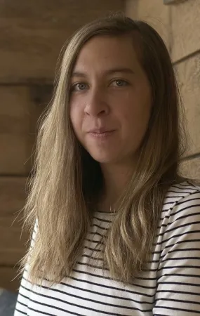 Elizabeth has long blond hair and a striped shirt on. 