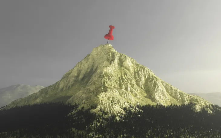 A mountain with a red thumbtack at the top, indicating a goal