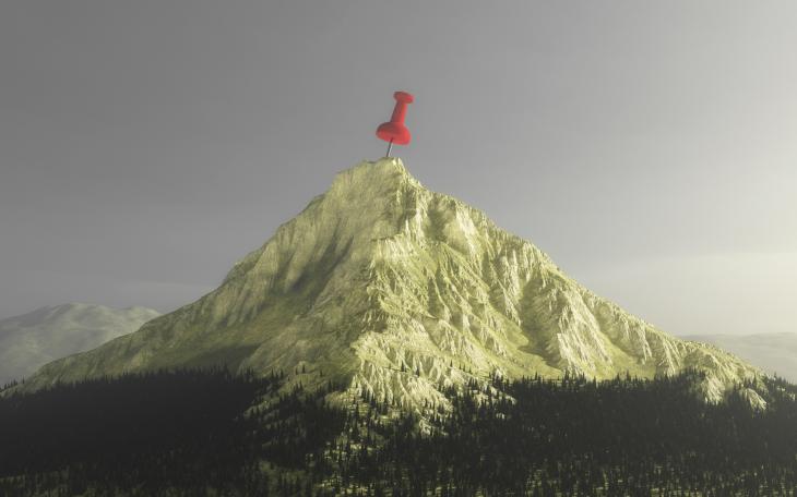 A mountain with a red thumbtack at the top, indicating a goal