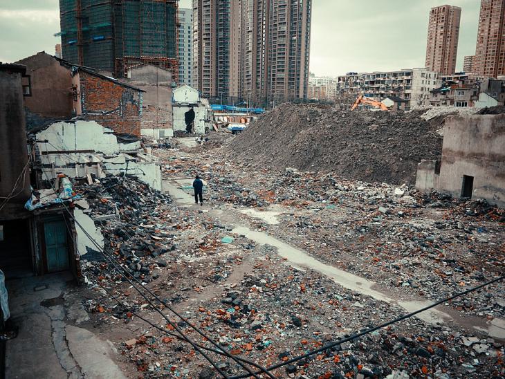 A person standing among massive piles of debris with skyscrapers in the background