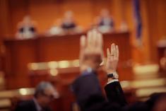 Hands raised in the foreground with a council sitting in the background out of focus